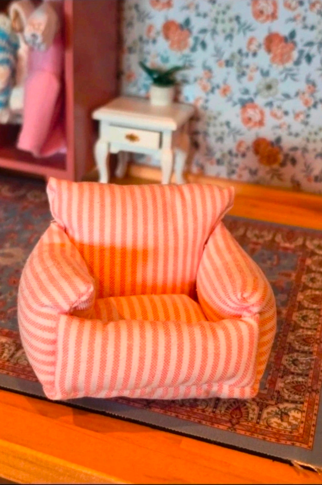 Fauteuil miniature rayé rose et blanc en situation dans un salon de maison de poupée