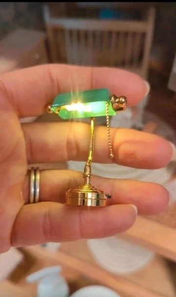 Lampe de banquier miniature allumée sur un bureau