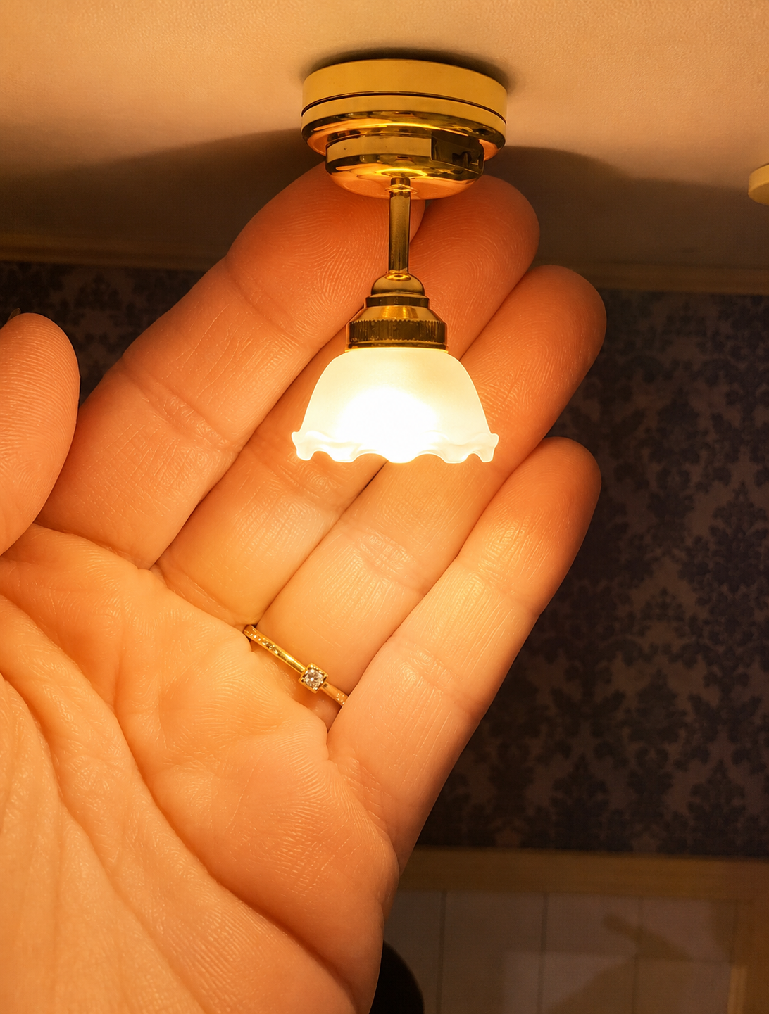 Plafonnier miniature doré fixé au plafond d'une maison de souris