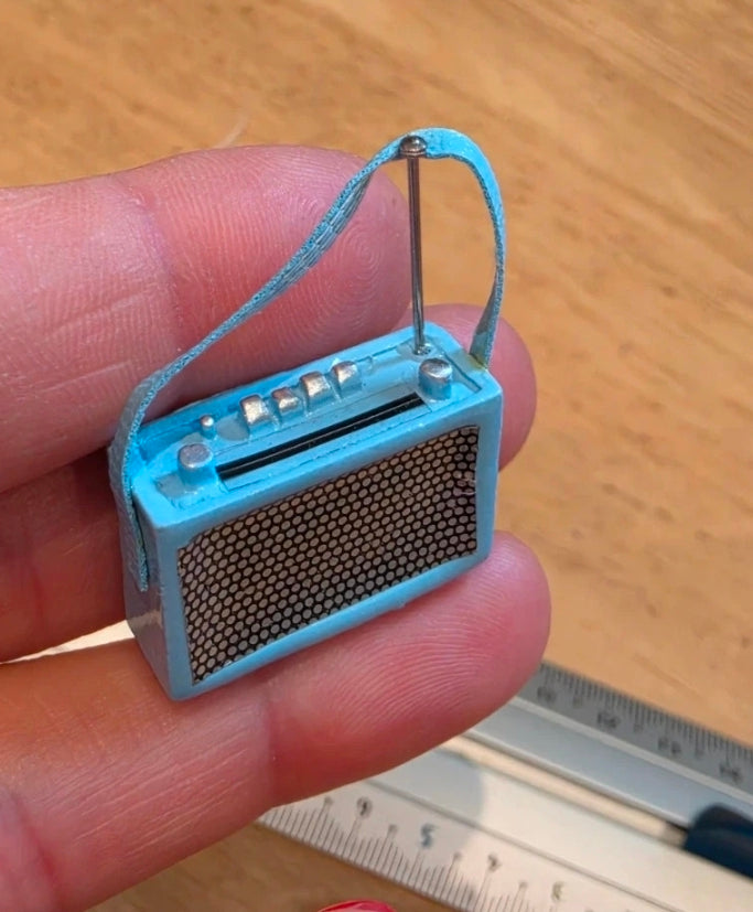Radio miniature métallique en situation dans une chambre de maison de poupée