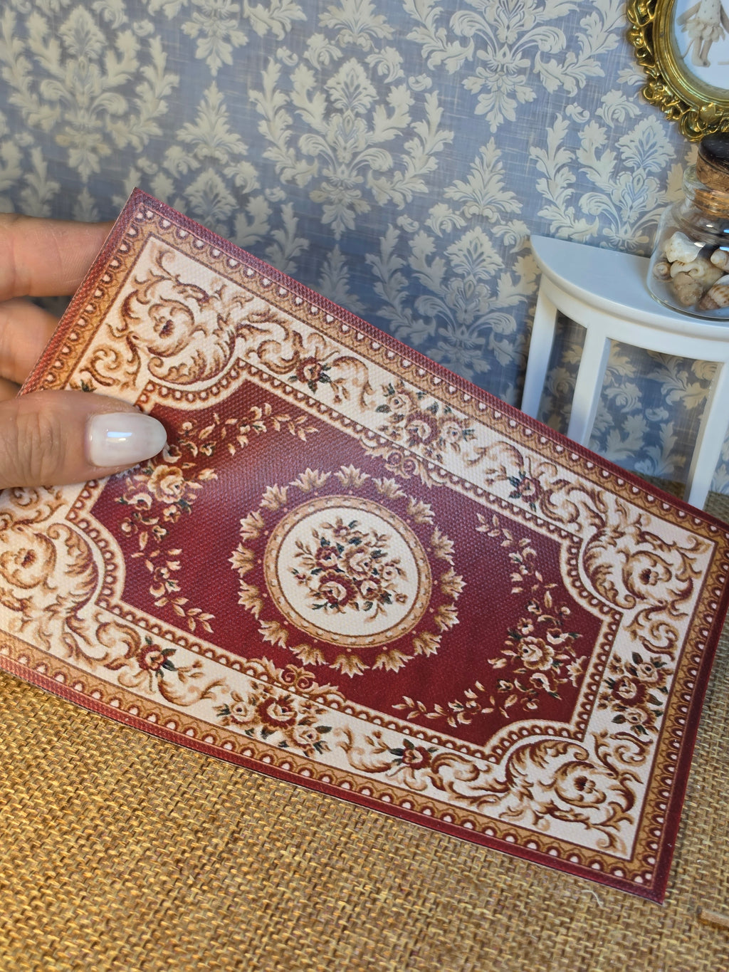 Détail des motifs bordeaux, crème et doré du tapis miniature